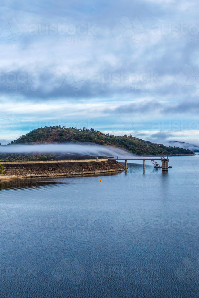 Vertical Aerial view of the Glenbawn Dam wall leading towards the surrounding mountain landscape - Australian Stock Image