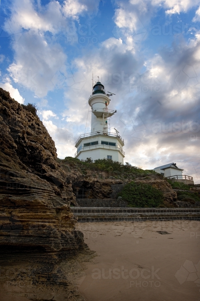 Vertical aspect of a lighthouse with cliffs in foreground - Australian Stock Image