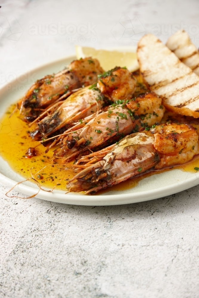 vertical close up shot of sautéed shrimps with a slice of lemon and some toast in the side - Australian Stock Image