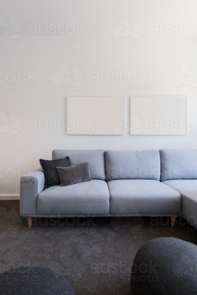 Vertical image of pastel blue sofa with blank artwork above - Australian Stock Image