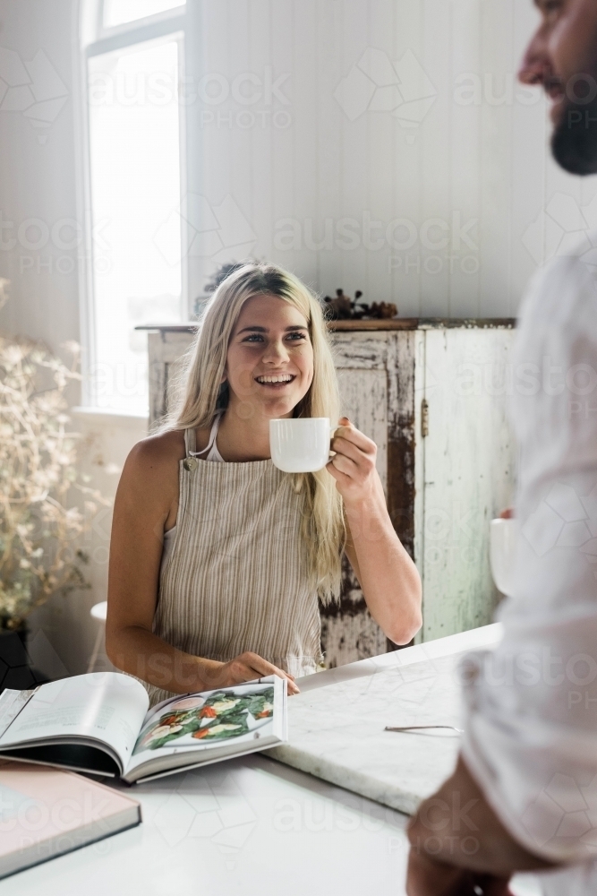 Vertical shot of a blonde hair woman drinking a cup of coffee - Australian Stock Image