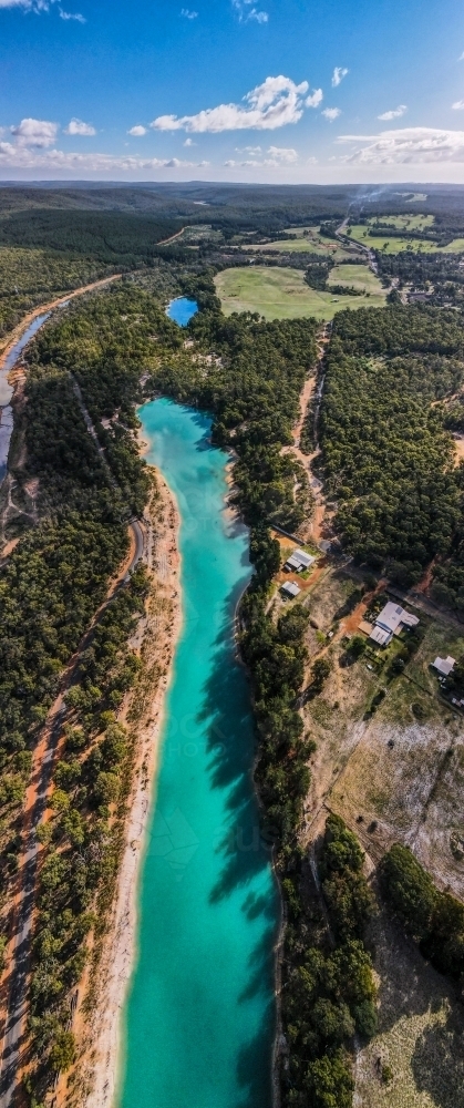 vertical shot of a blue lake surroundedwith green trees on a sunny day with bright blue skies - Australian Stock Image