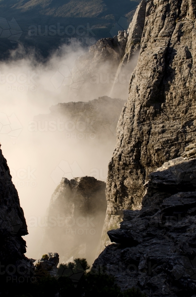 Vertical shot of a cliff face hidden in mist - Australian Stock Image
