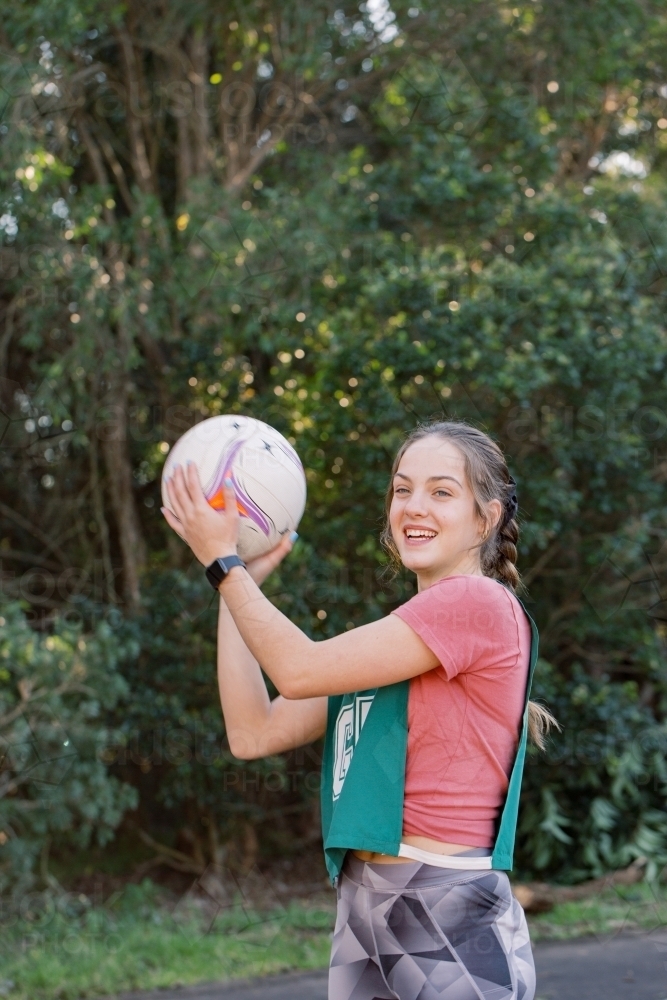 vertical shot of a young woman in ponytail wearing sports clothes holding a ball on a sunny day - Australian Stock Image