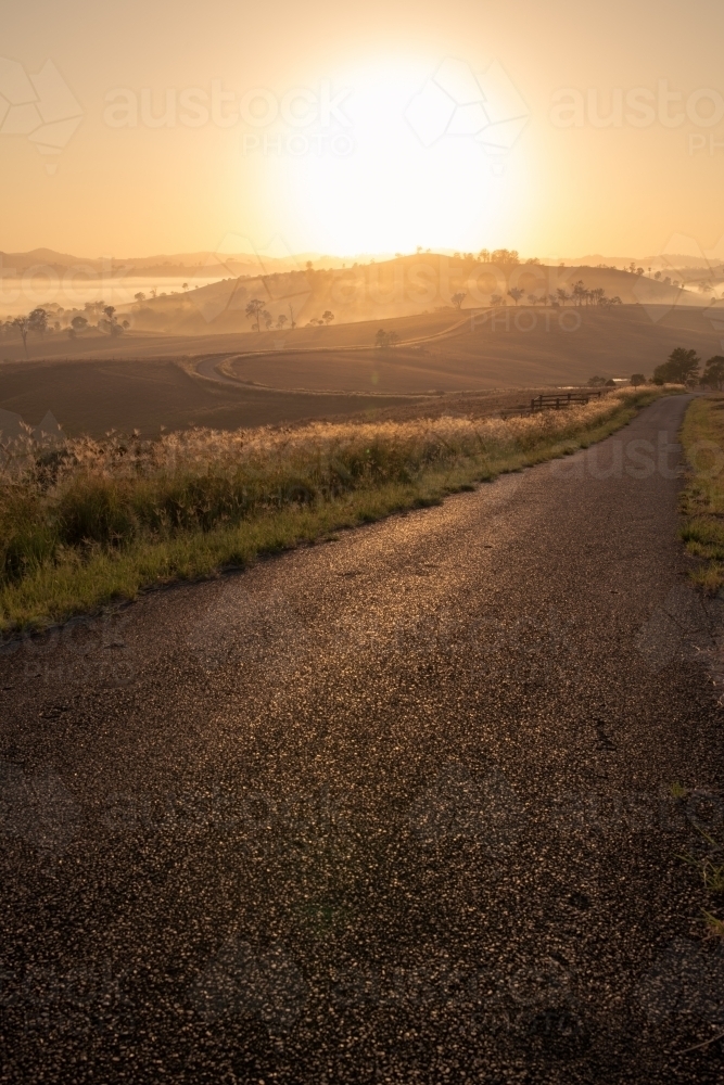 Vertical shot of an empty road heading toward hills at dawn - Australian Stock Image