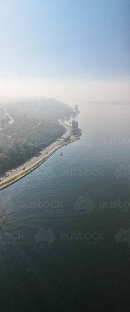 vertical shot of an island with smoky surrounding with purple and blue skies - Australian Stock Image