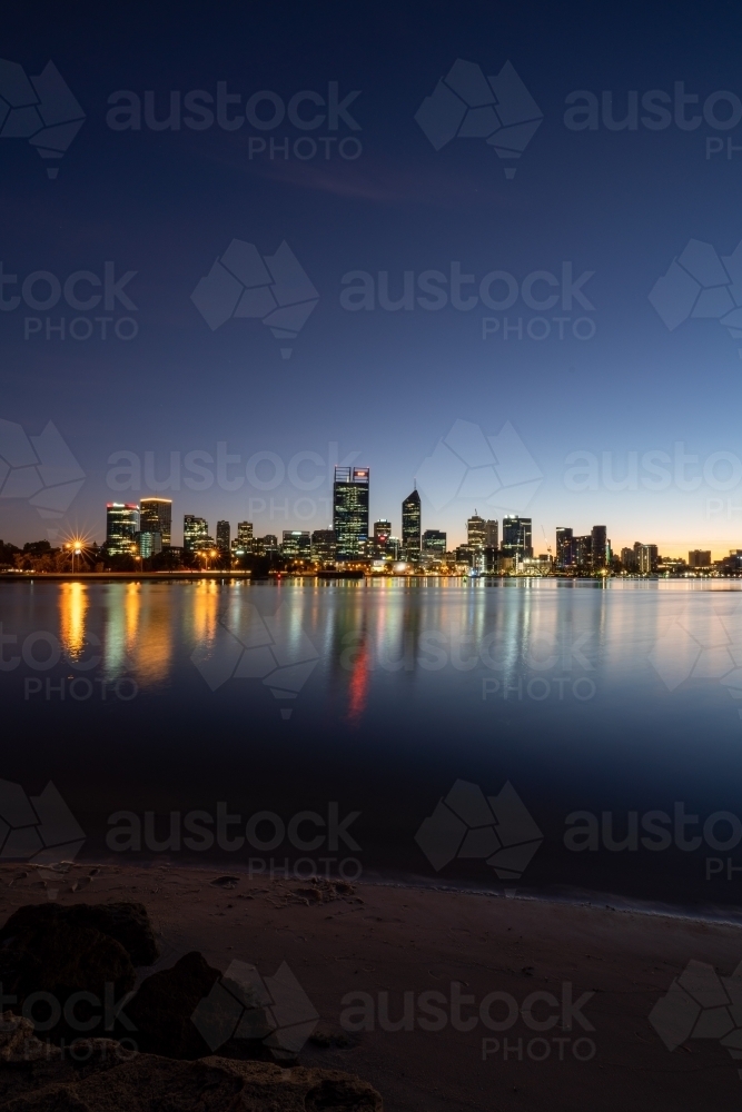 vertical shot of buildings reflecting in a lake with black, blue and white skies about - Australian Stock Image