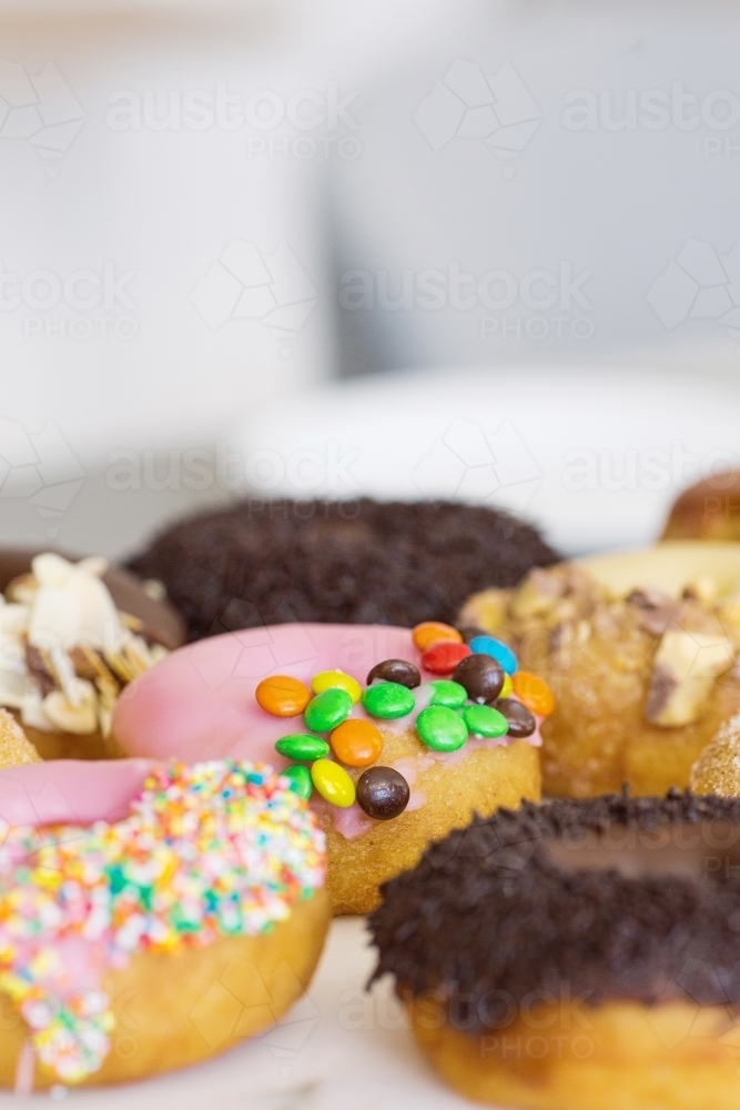 Vertical shot of different kinds of flavored donuts on a white plate. - Australian Stock Image