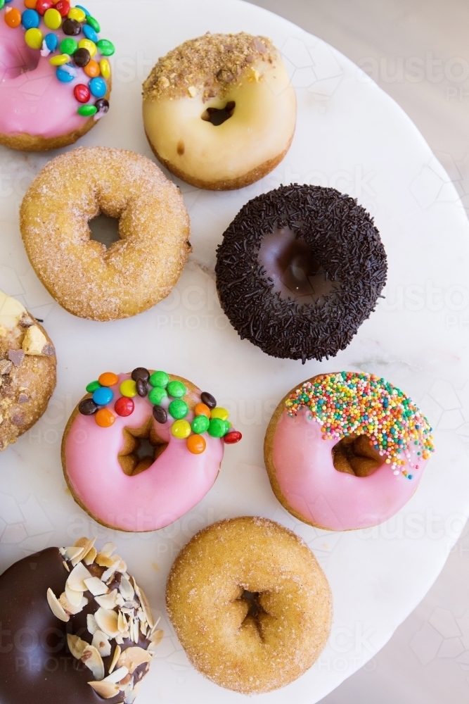 Vertical shot of different kinds of flavored donuts on a white plate. - Australian Stock Image