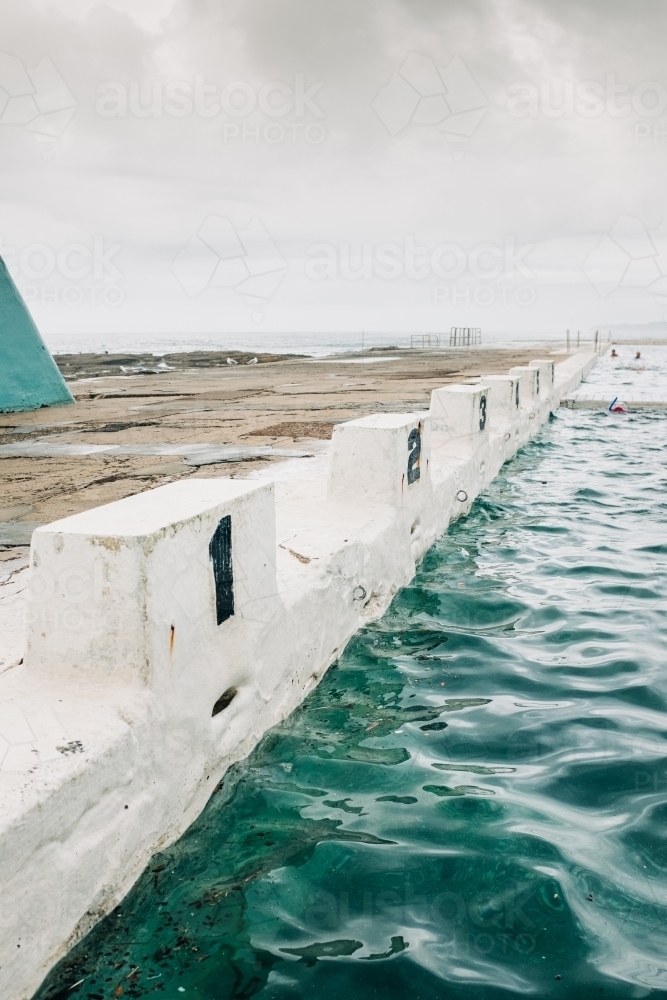 vertical shot of empty diving block stands with numbers in an ocean pool on a cloudy day - Australian Stock Image