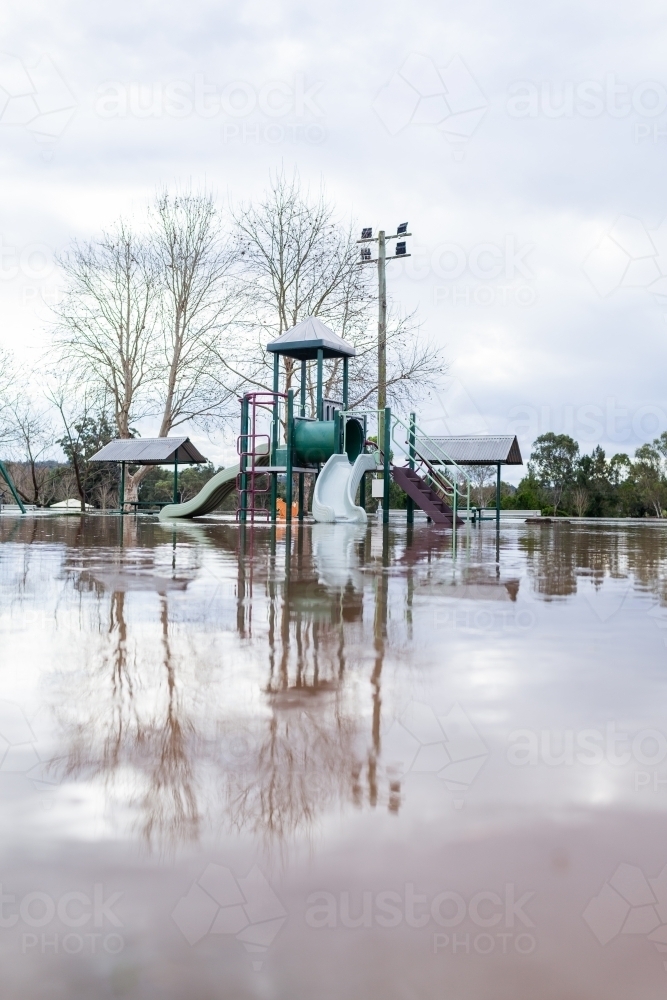 Vertical shot of park with child's play equipment covered in floodwater during flood - Australian Stock Image