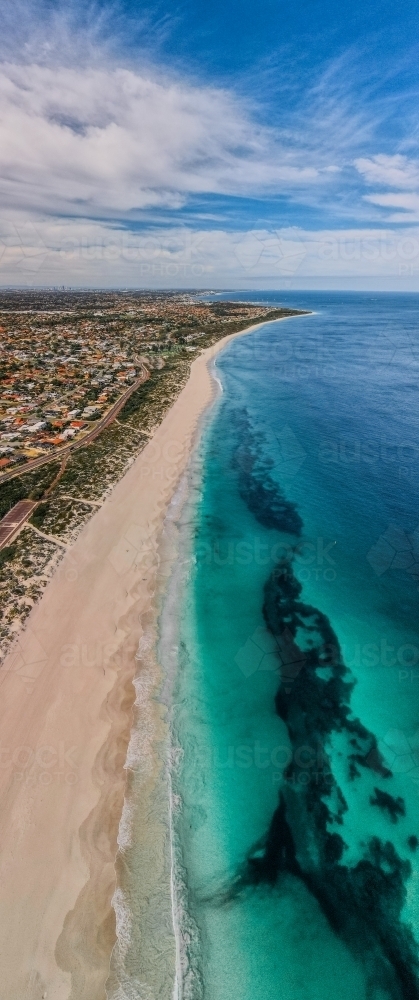 vertical shot of Summers in Perth with white sand shoreline, green grass and ocean water and clouds - Australian Stock Image