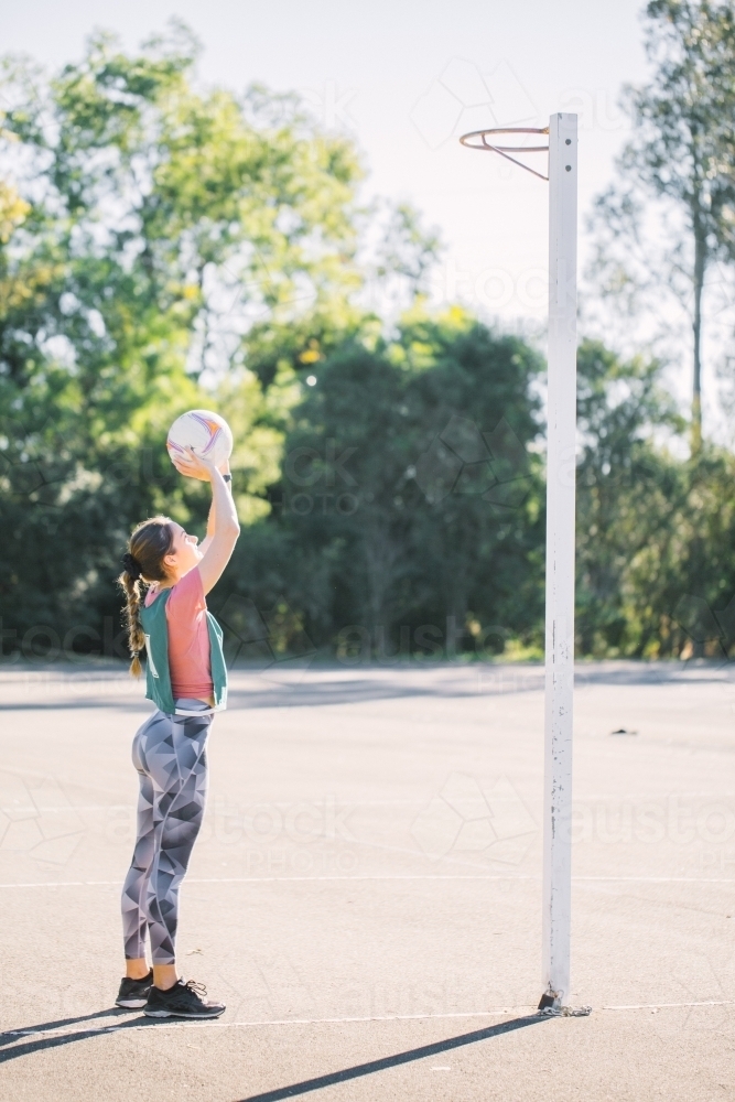 vertical shot of young woman about throw a net ball to the net on a sunny day - Australian Stock Image