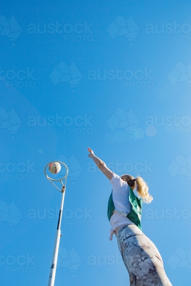 Image of vertical shot of young woman throwing net ball in mid air on a ...