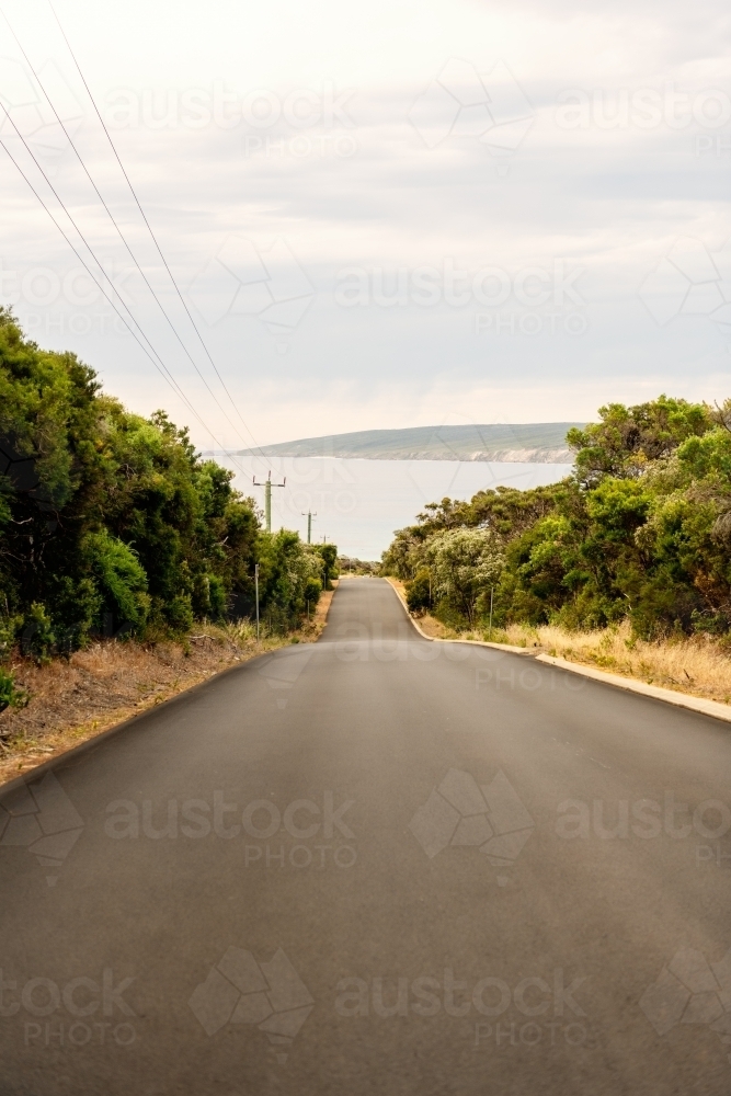 vertical view of road leading down to the ocean - Australian Stock Image