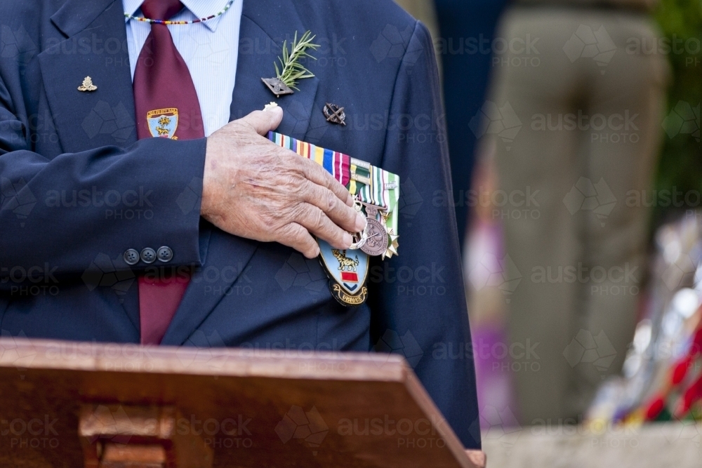 Veteran with his hand on his heart and medals during an Anzac service - Australian Stock Image