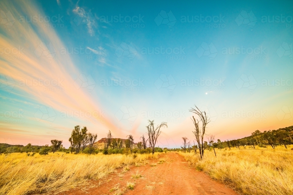 Vibrant colors of the sky during dawn in the Australian outback along an outback track - Australian Stock Image