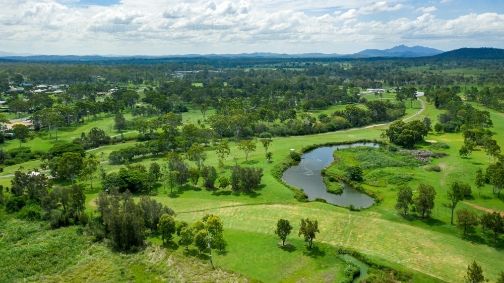 Vibrant green summer landscape showing a golf course and hills in the distance - Australian Stock Image
