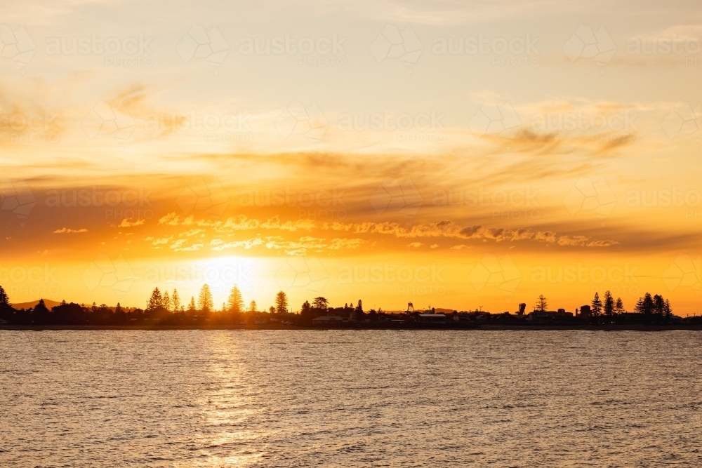 Vibrant orange sunset over Stockton NSW with view across the water - Australian Stock Image