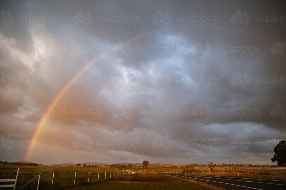 Image of Vibrant rainbow arches over a rural landscape after a storm ...