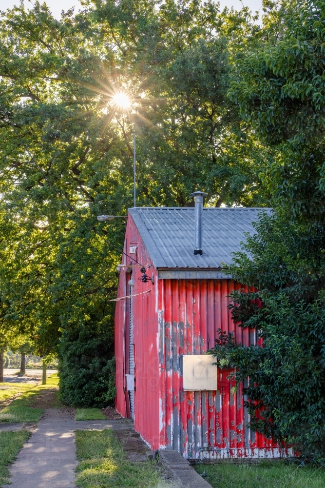 Vibrant red shed nestled among bush green trees - Australian Stock Image