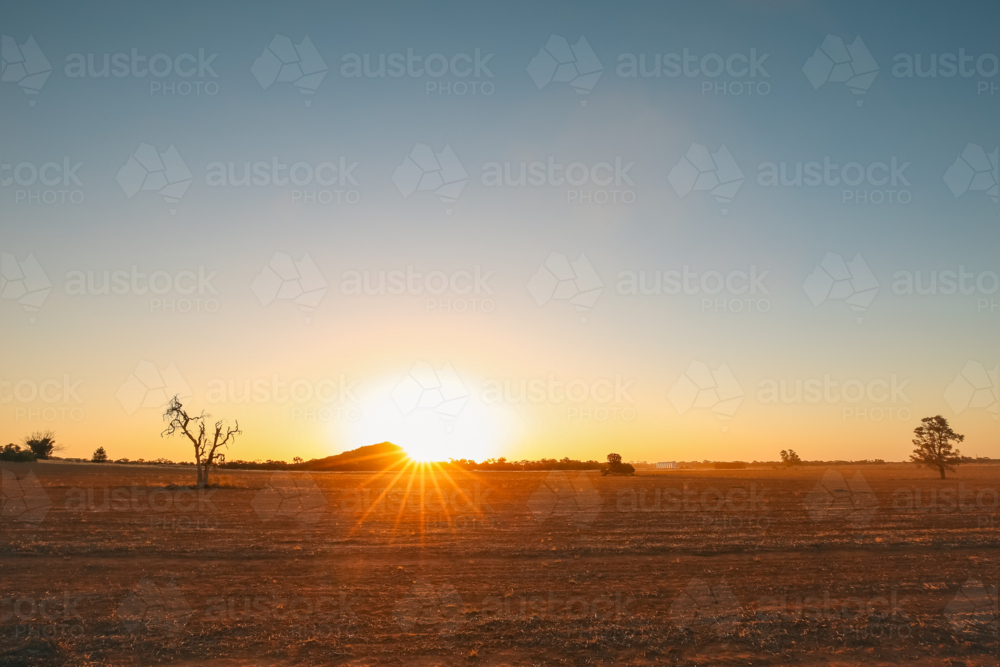 Vibrant sunburst as sun sets behind Pyramid Hill rock formation in Central Victoria - Australian Stock Image