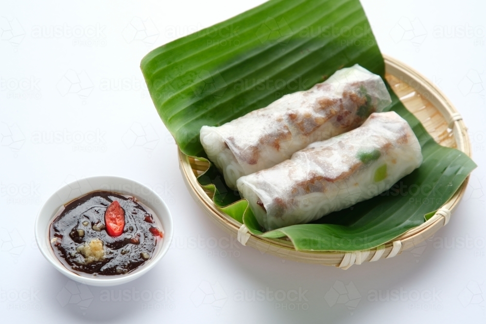Image of Vietnamese spring rolls on leaf in bamboo bowl with dipping ...