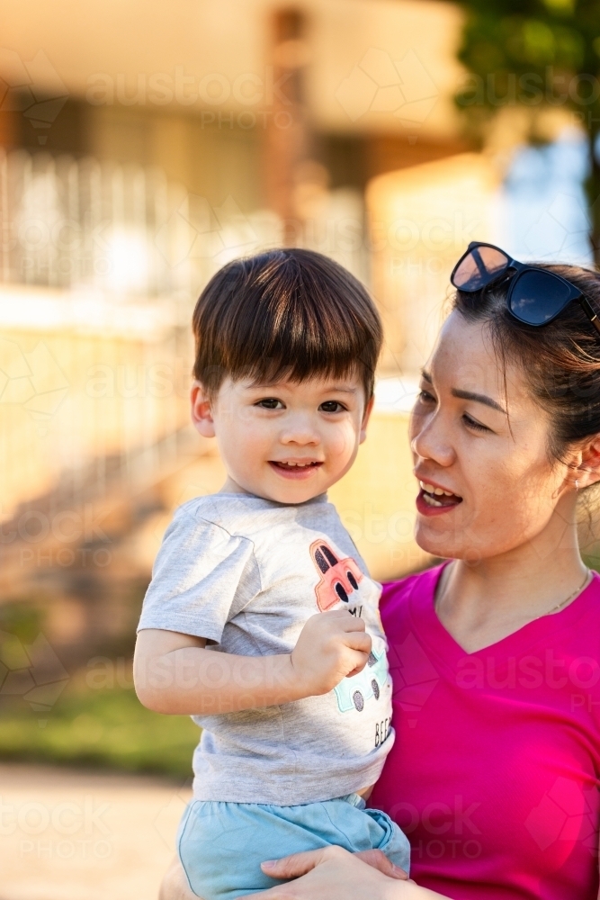 Vietnamese woman holding  son smiling together outside home - Australian Stock Image