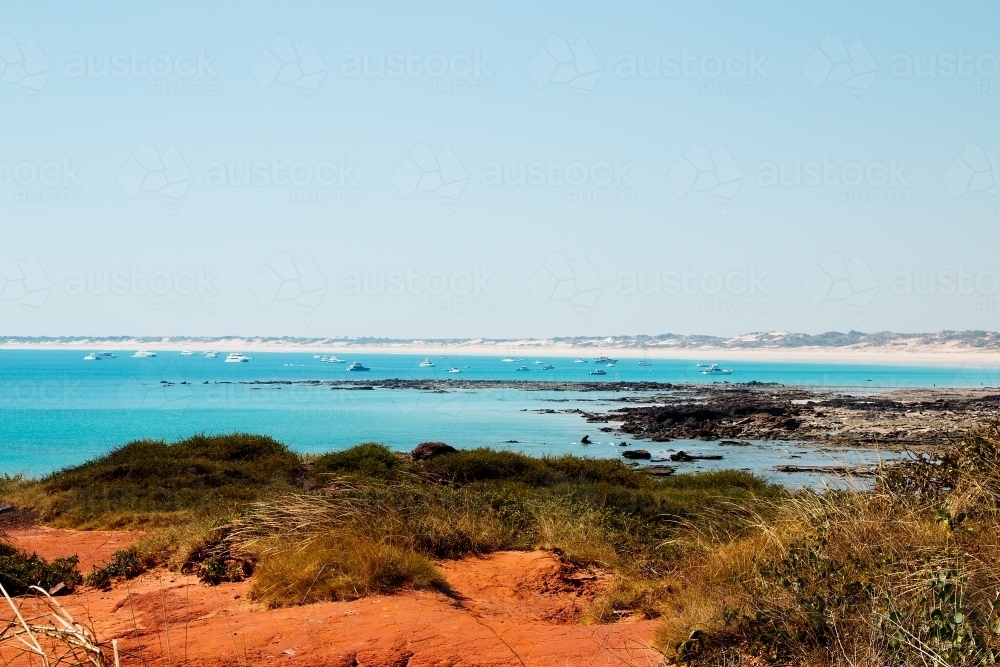 view across calm blue bay with boats and beach in background - Australian Stock Image