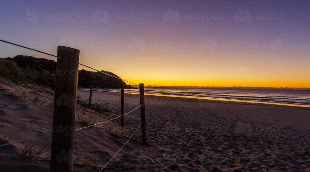 view across sandy beach towards sunset - Australian Stock Image
