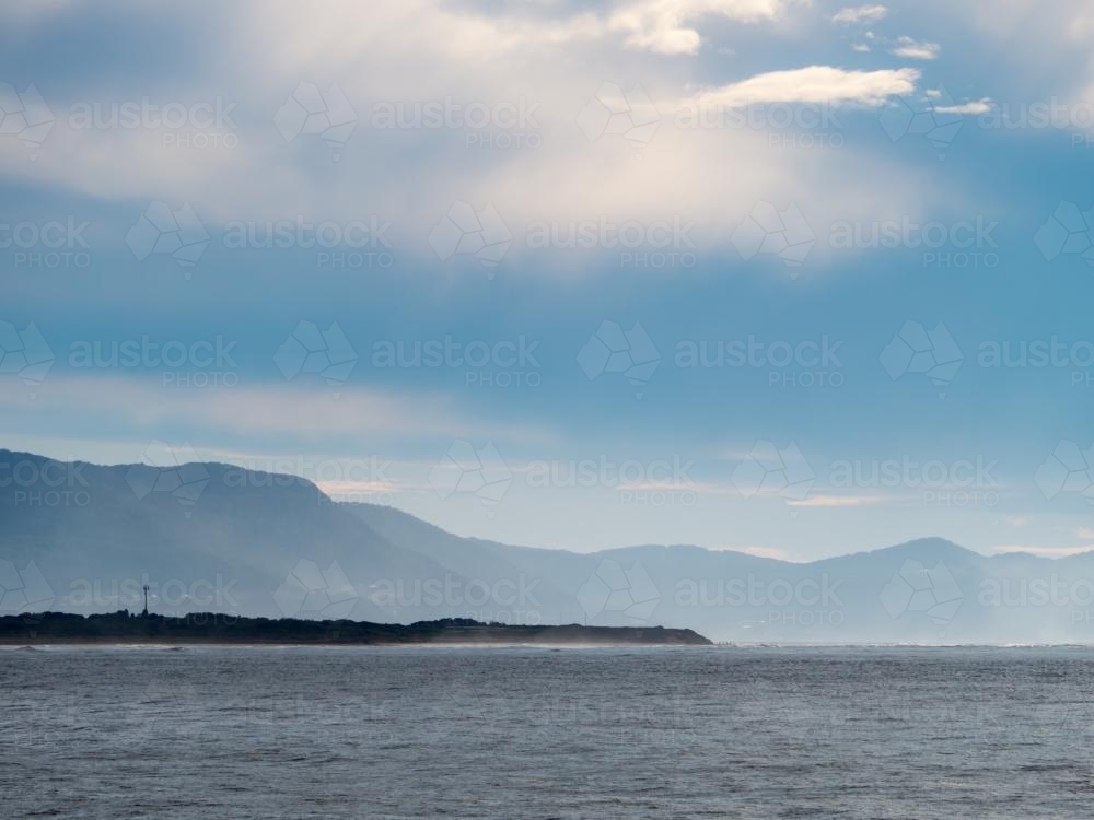 View across the sea towards a hazy mountain range - Australian Stock Image