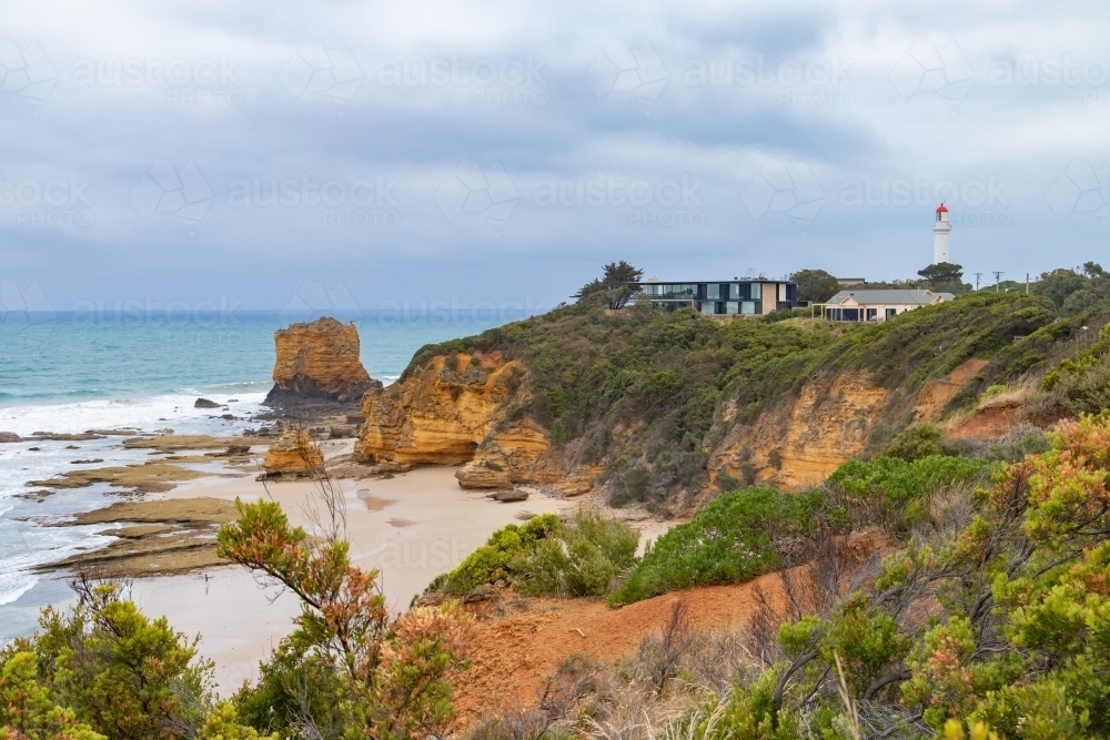 view along coastline to lighthouse and houses - Australian Stock Image