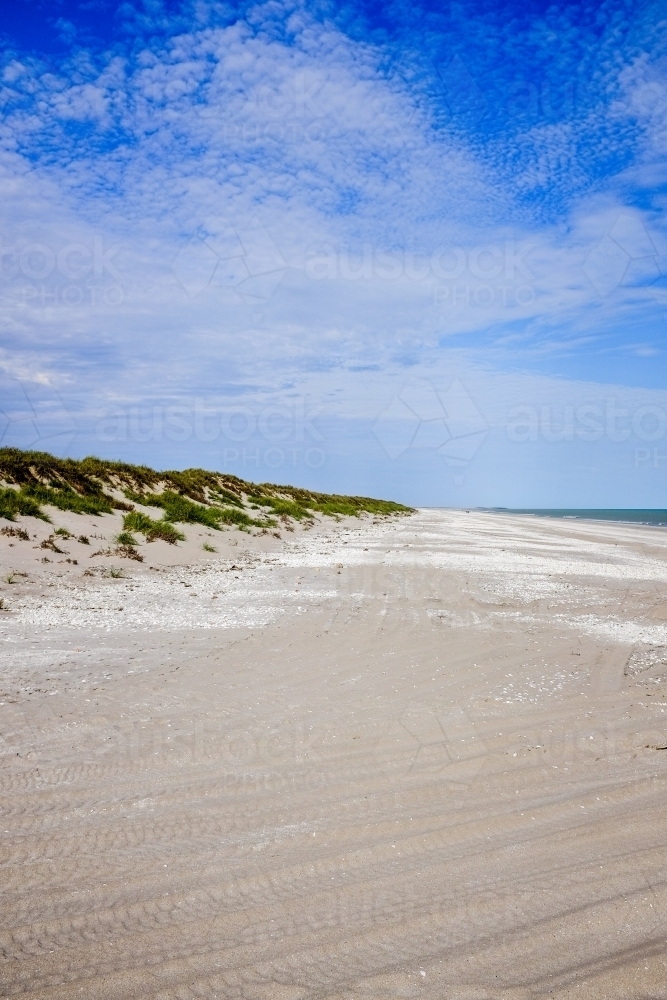 View along white sandy beach with blue cloudy sky - Australian Stock Image