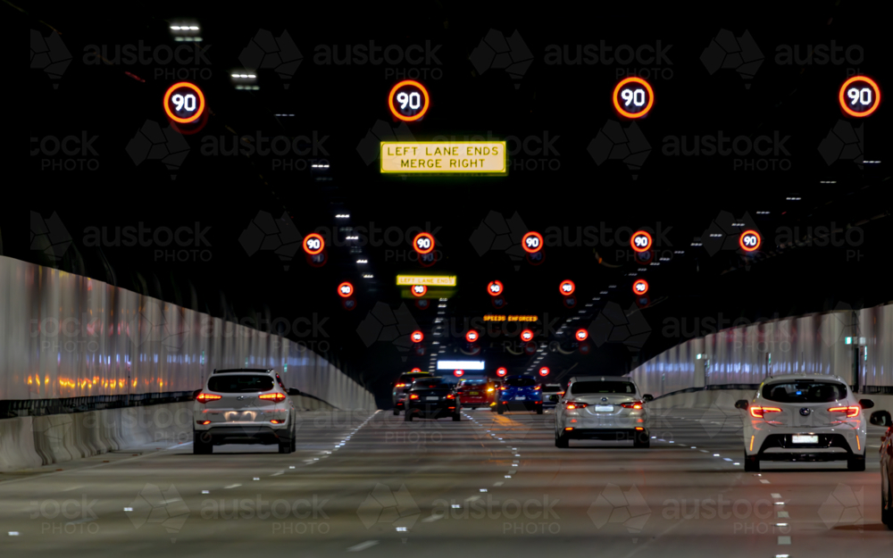 View from a car, Sydney toll road tunnel showing speed signs and four lanes with camera shake - Australian Stock Image