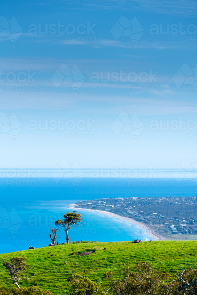 view from a grassy hilltop overlooks the coastline and turquoise sea - Australian Stock Image