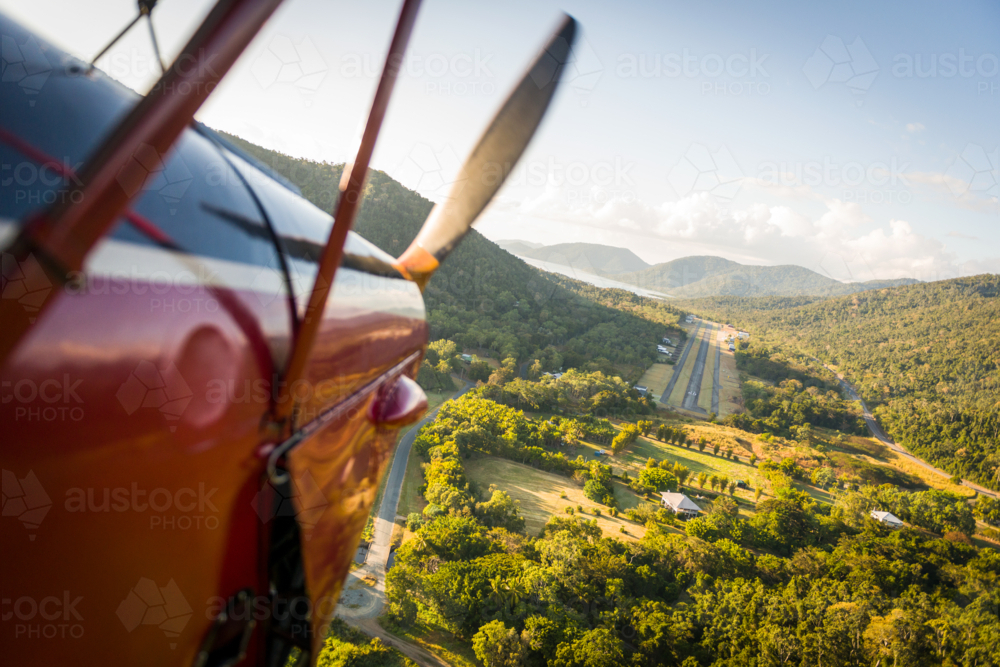 View from biplane approaching airstrip through tropical mountain valley in late afternoon light. - Australian Stock Image