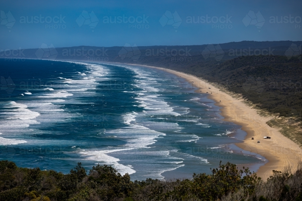 View from Double Island Point looking at breaking waves and vehicles on Cooloola Beach - Australian Stock Image
