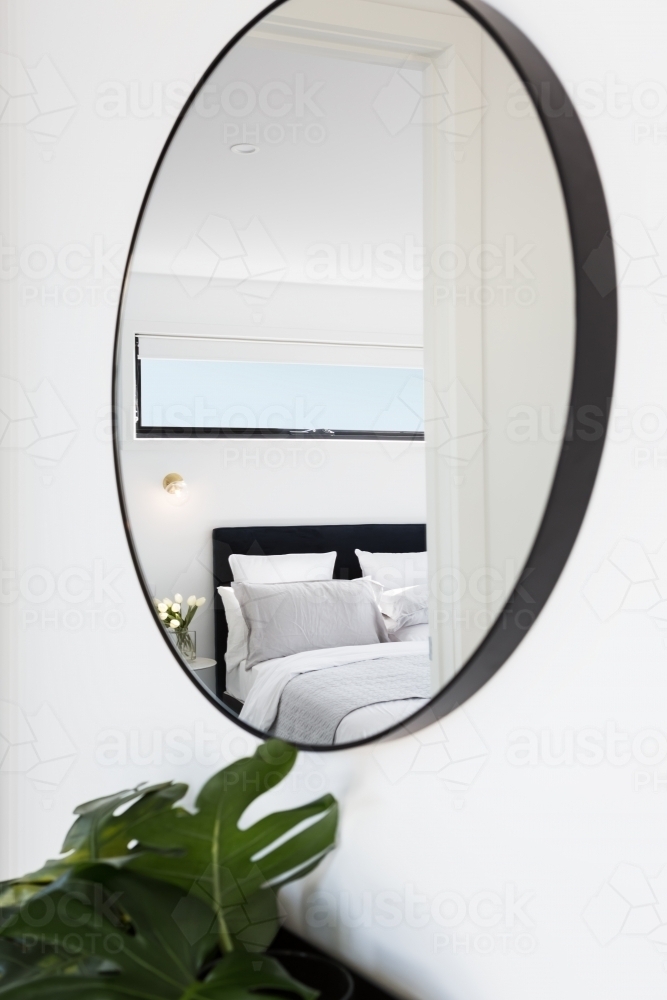 View of a luxury bedroom reflected in a hallway mirror - Australian Stock Image