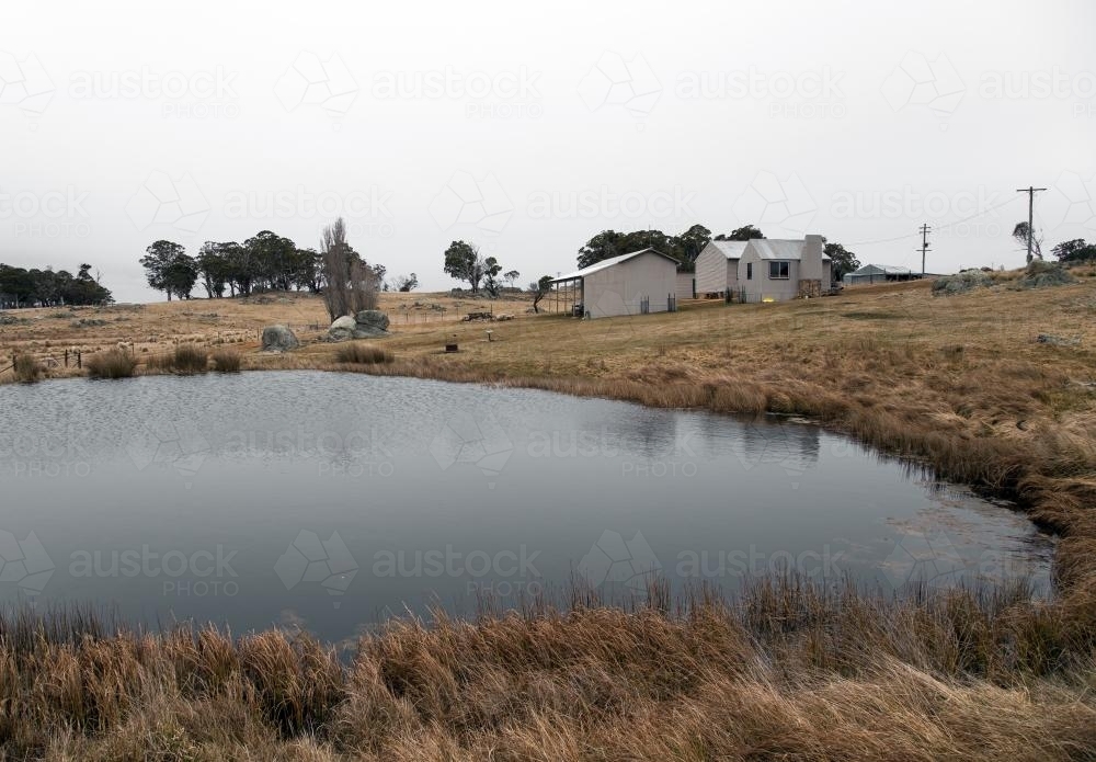 View of a rural farm house across a dam - Australian Stock Image