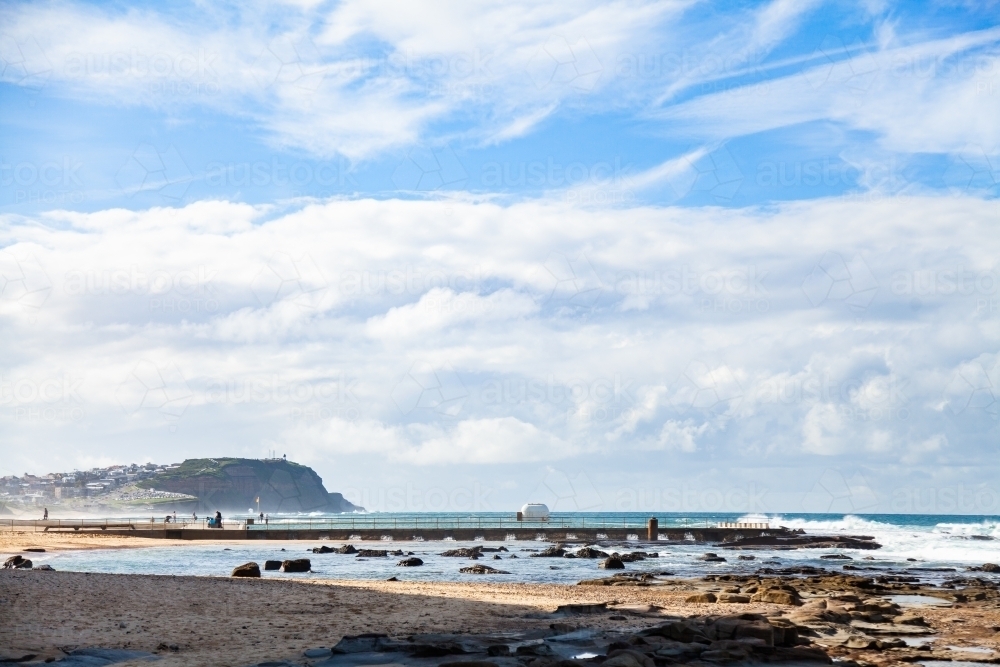 view of Aussie beach and headland covered in sea spray - Australian Stock Image