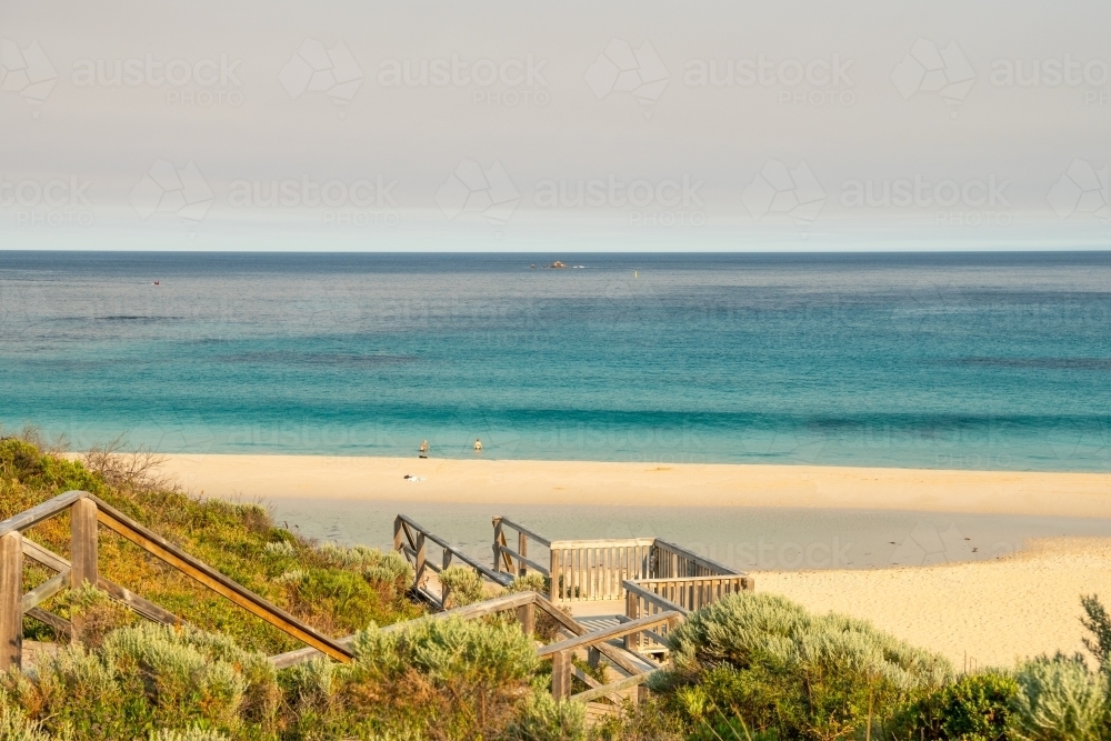 View of beach with swimmers and ocean from top of staircase - Australian Stock Image
