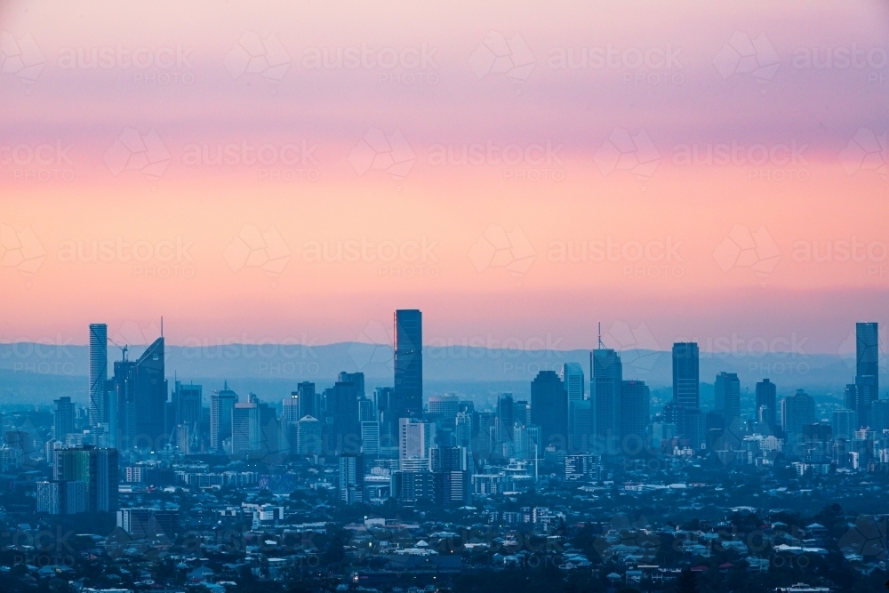 View of Brisbane City skyline from Mt Gravatt Lookout with colourful smoke haze in the sunset - Australian Stock Image