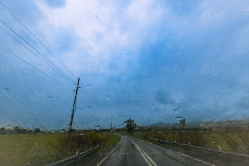 View of countryside on dark stormy day through windshield of vehicle - Australian Stock Image