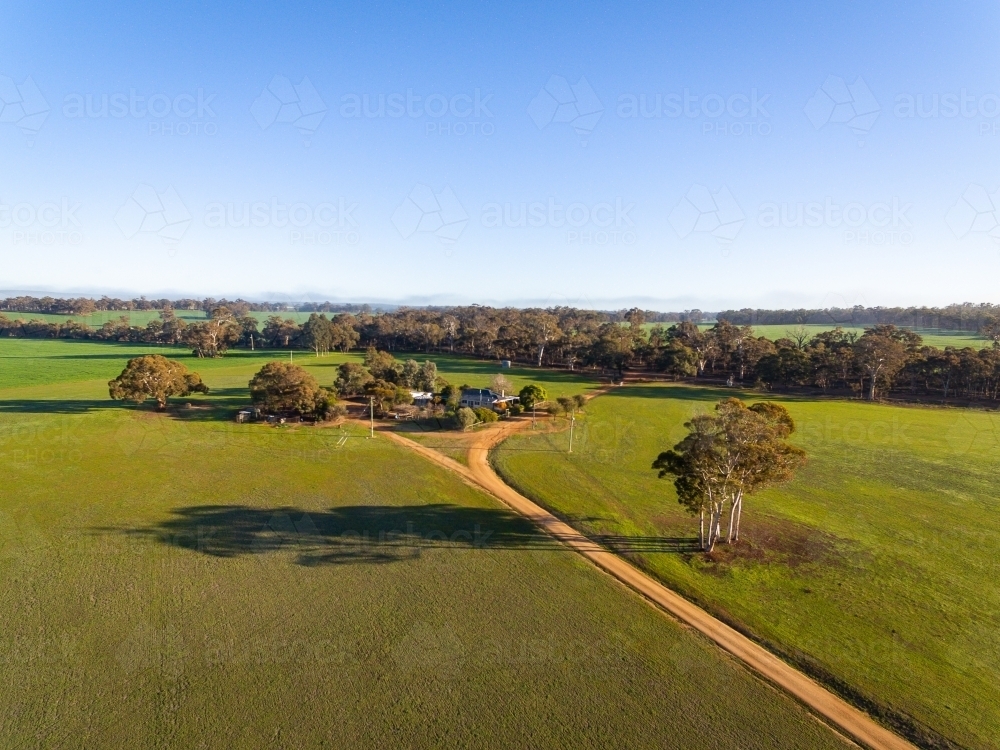 view of farm showing driveway and homestead with bush and blue sky - Australian Stock Image