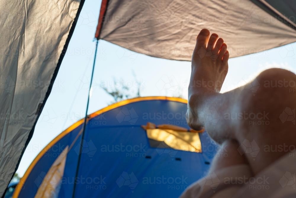 View of legs and feet of a camper relaxing in tent - Australian Stock Image