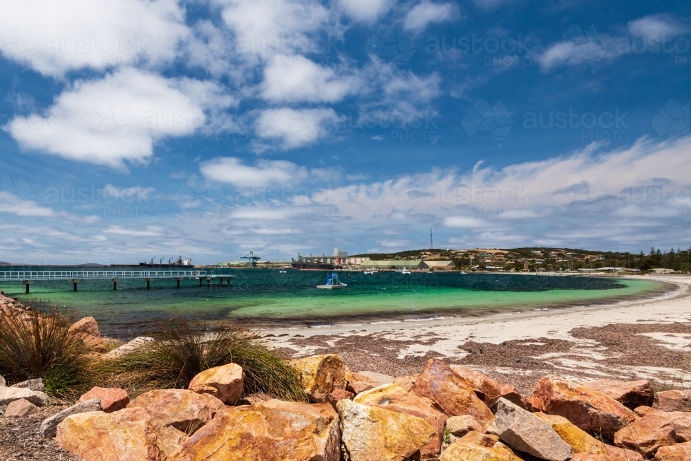 View of Port across a bay with colourful rock wall in foreground - Australian Stock Image