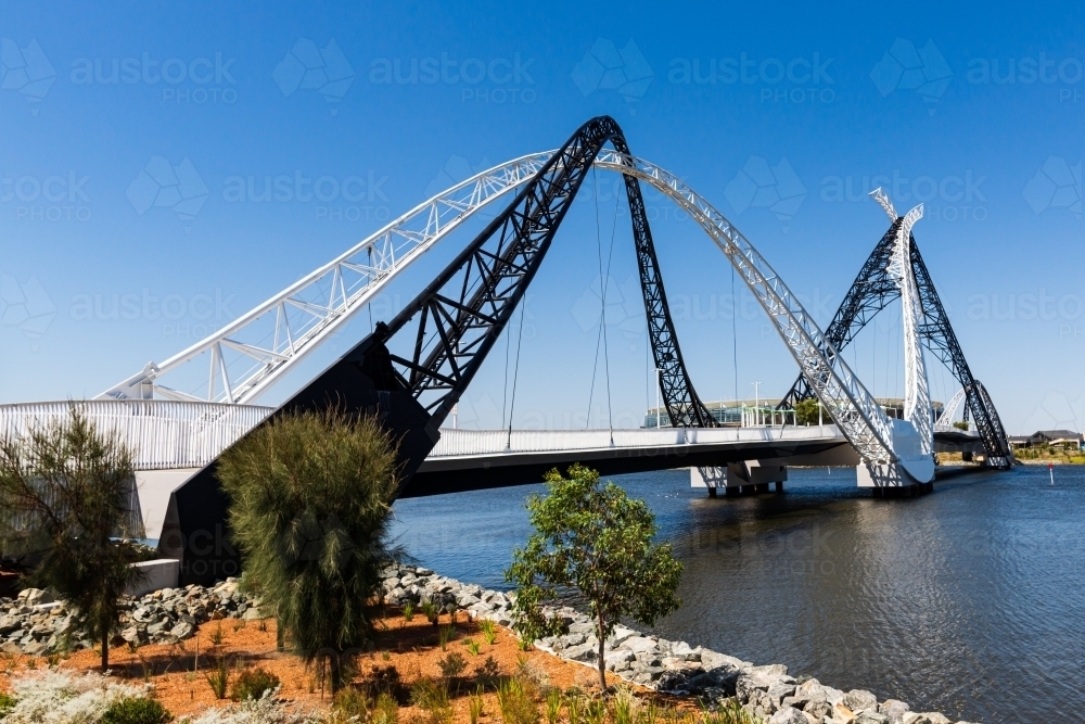 View of the unusual Matagarup Bridge with large sports stadium in the background and clear blue sky - Australian Stock Image