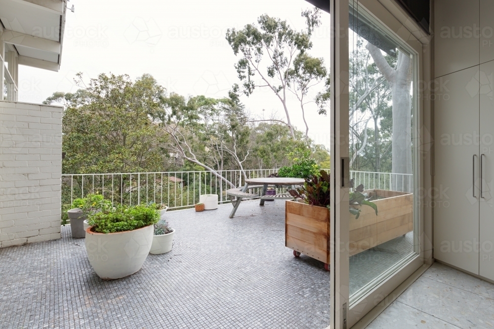 View of treetops from large mosaic tiled terrace in Australian luxury home - Australian Stock Image