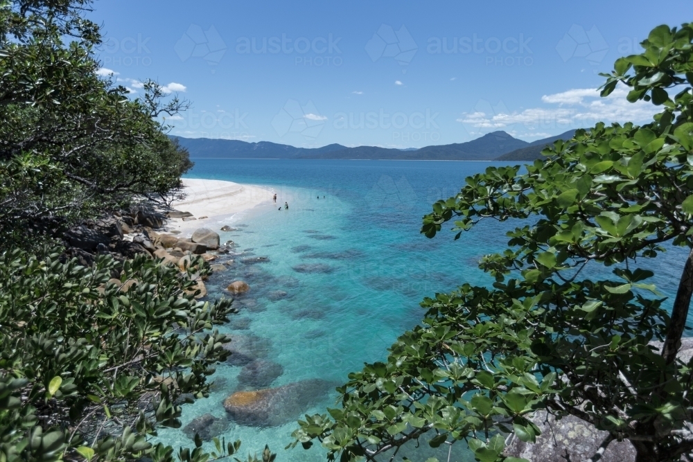View of  white Sandy Beach surrounded by blue ocean and green rainforest - Australian Stock Image