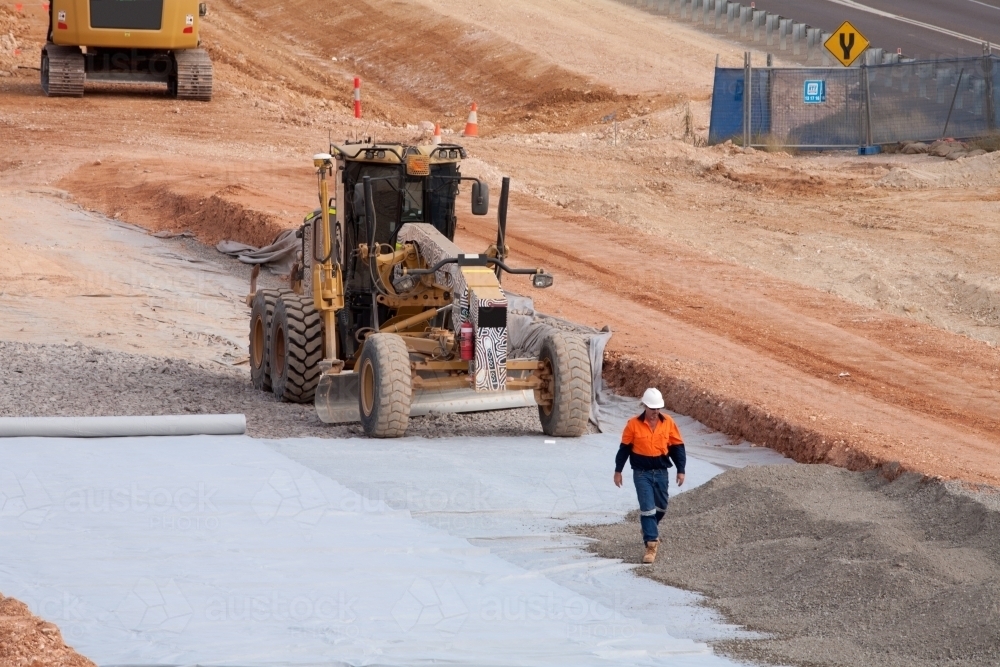 View of workers and heavy machinery on a road construction worksite - Australian Stock Image